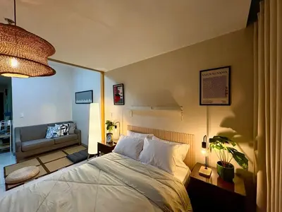 a bedroom with a large bed and a living room at Japandi Haven with Uptown Mall Fountain View One Uptown BGC in Manila