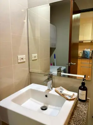 a bathroom with a white sink and a mirror at Japandi Haven with Uptown Mall Fountain View One Uptown BGC in Manila