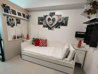 a small room with a white bed with hearts on the wall at Lornas Staycation in Manila