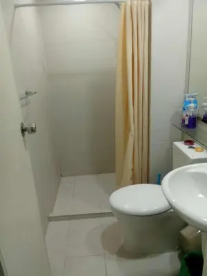 a bathroom with a shower and a toilet and a sink at Cozy Condos at Azure Urban Resort in Manila