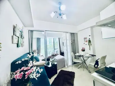 a woman sitting on a couch in a living room at Cozy Condos at Azure Urban Resort in Manila