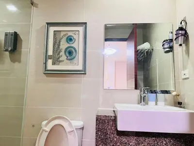 a bathroom with a toilet and a sink and a mirror at Easyworld One Uptown Residence BGC in Manila