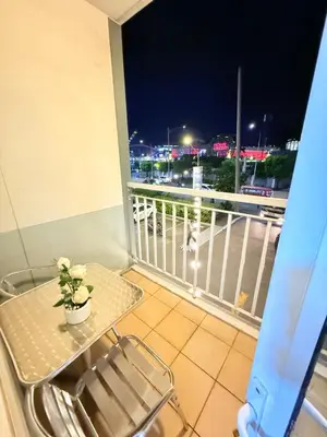 a table and a chair on a balcony at night at Shell Residences Prime By Paul in Manila