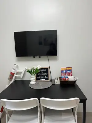 a black table with two white chairs and a tv at 3Ms Homestay Shore in Manila