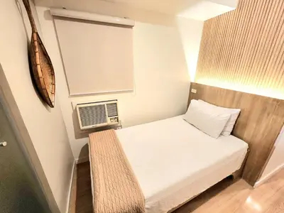 a small room with a bed and a window at Stone House Hotel Manila in Manila