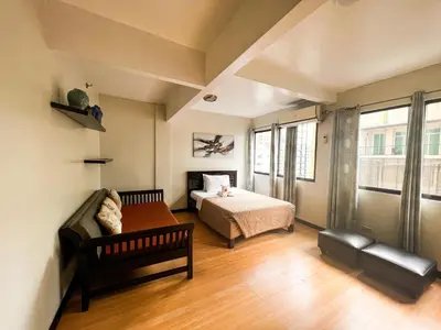a bedroom with a bed and a couch in a room at Stone House Hotel Manila in Manila
