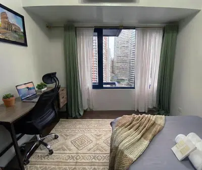 a bedroom with a bed and a desk and a window at Stylish 1BR Air Residences Wifi & Netflix in Manila