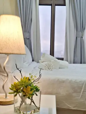 a bed with a lamp and a vase of flowers on a table at GOUTEI Homestay - The Radiance Manila Bay in Manila