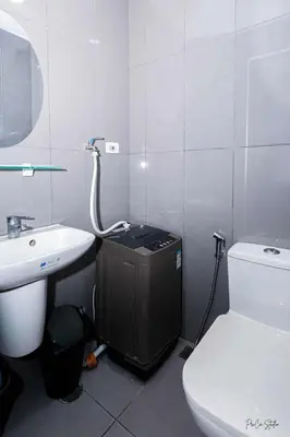 a white bathroom with a toilet and a sink at Snooze & Stay in Manila