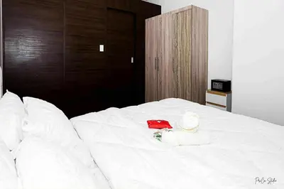 a white bed with a red hat on it at Snooze & Stay in Manila