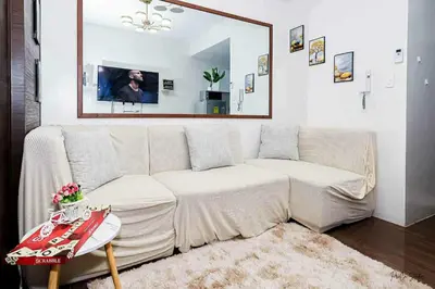 a living room with a white couch and a mirror at Snooze & Stay in Manila