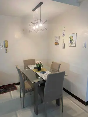a dining room table with chairs and a chandelier at Staycation by Capri in Manila