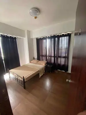 a bedroom with a bed and two large windows at Staycation by Capri in Manila
