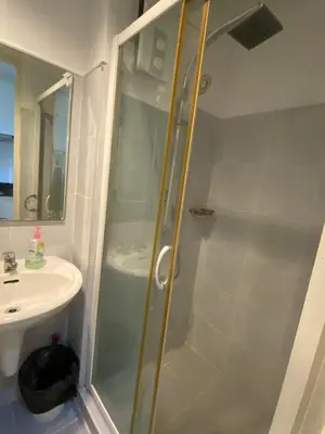 a shower with a glass door next to a sink at Stern Staycation Moa Sea Residences in Manila