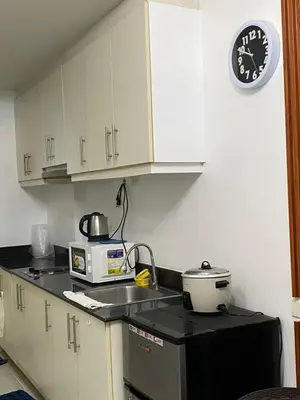 a kitchen with a microwave and a clock on the wall at Stern Staycation Moa Sea Residences in Manila