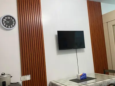 a room with a tv and a table with a clock at Stern Staycation Moa Sea Residences in Manila