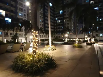 a courtyard lit up at night with trees and lights at Queen Pia Condotel in Manila