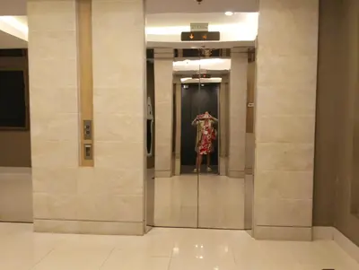 a woman in a dress is standing in a elevator at Queen Pia Condotel in Manila
