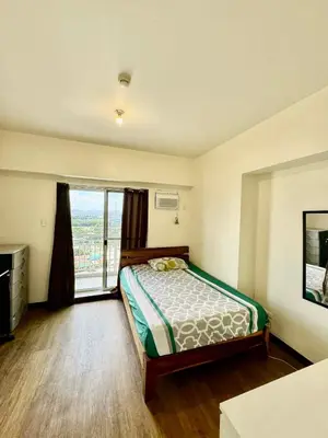 a bedroom with a bed and a large window at Vacation at Munti in Manila