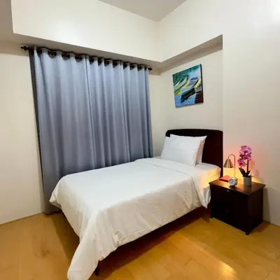 a bedroom with a large white bed and a window at Entire 2BR apartment in BGC in Manila