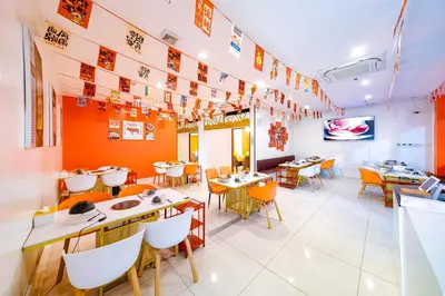 a restaurant with orange walls and tables and chairs at Luna Hotel by RedDoorz near MOA in Manila