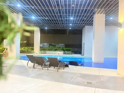 a pool in the middle of a building with chairs at 1 Bedroom Near Mall of Asia in Manila