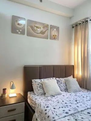a bedroom with a bed with pillows and a table at Transient Home Lancin in Manila