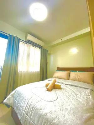 a teddy bear sitting on a bed in a bedroom at Jay's Staycation at Shore Residences Pasay in Manila
