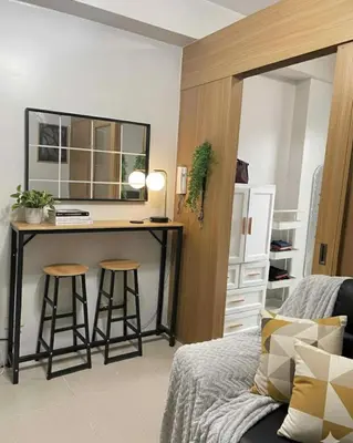a bedroom with a desk and two stools in front of a bed at Staycation in Pasay near Moa in Manila