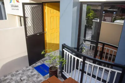 a porch with a yellow door and a potted plant at CLBC Residences New home in the heart of Laguna in Biñan