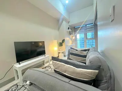 a living room with a couch and a flat screen tv at Elegant Central 1BR BGC 11P Uptown Parksuites T2 in Manila