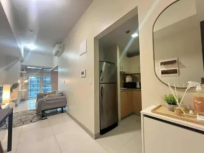 a kitchen with a refrigerator and a living room at Elegant Central 1BR BGC 11P Uptown Parksuites T2 in Manila
