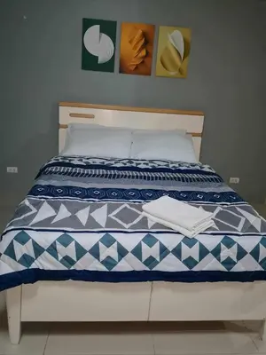 a bed with a blue and white comforter on it at Neri Ann's Comfort Escape in Manila