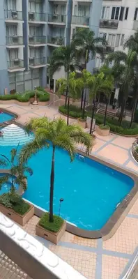 a large swimming pool with a palm tree in front of a building at Neri Ann's Comfort Escape in Manila