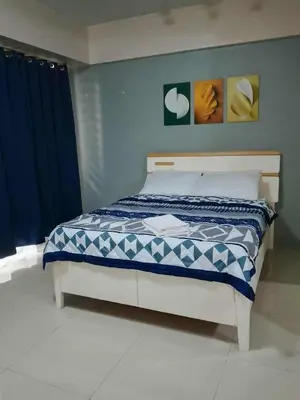 a bedroom with a bed with a blue and white comforter at Neri Ann's Comfort Escape in Manila