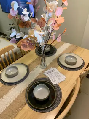 a table with four plates and a vase with flowers at 2BR 38th flr SIESTA SPACE in PRISMA Residences in Manila