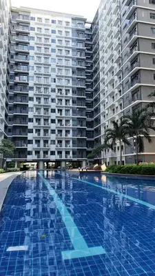 a large swimming pool in front of a large building at Cozy staycation 1BR with WiFi, Netflix and more at Shore 3 MOA by Angels Cozy Corner in Manila