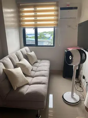 a living room with a couch and a fan at 2 bedroom condo at Leaf Residences Muntinlupa in Manila