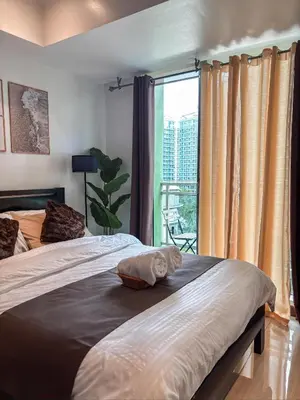 a bedroom with two beds and a large window at Premiere Staycation in Manila