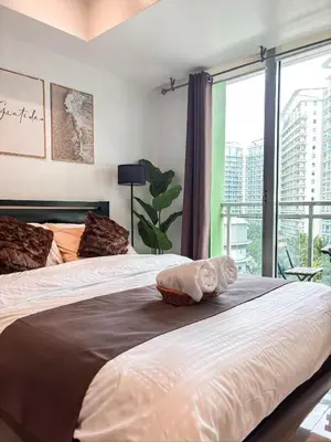 a bedroom with two beds and a large window at Premiere Staycation in Manila