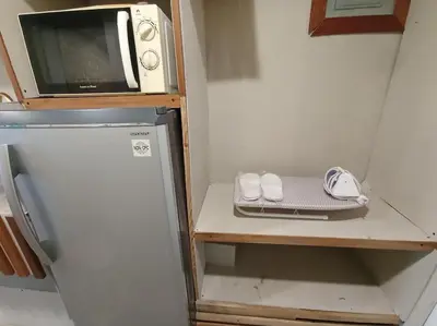 a small kitchen with a microwave and a refrigerator at Benedict's Staycation in Manila