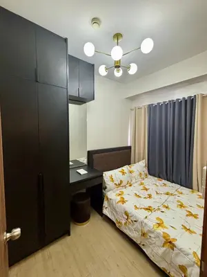 a bedroom with a bed and a desk and a bed and a cabinet at Casa Kanlungan at Spring Residences Tower 3 in Manila