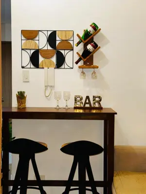 a table with two black stools and wine glasses at Melscape Lush Residence 1BR Unit in Sampong