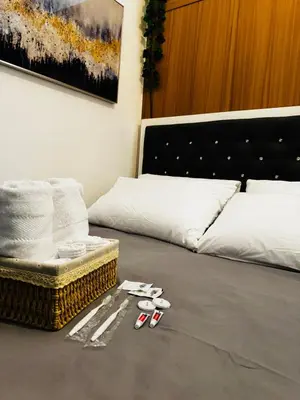 a room with a bed with towels and pairs of slippers at Melscape Lush Residence 1BR Unit in Sampong