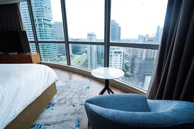 a bedroom with a bed and a chair and a window at Luxe 1BR Panorama Suite at Novotel Aqua in Manila