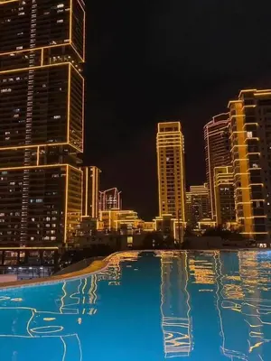 a large swimming pool with a city skyline at night at Luxe 1BR Panorama Suite at Novotel Aqua in Manila