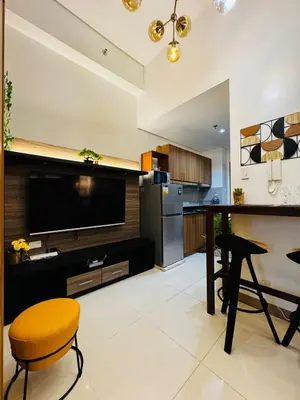 a kitchen with a large television and a table and chairs at Melscape Lush Residence 1BR Unit in Manila