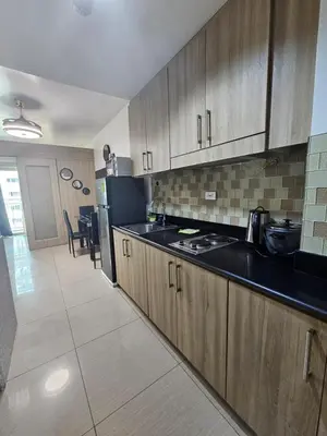 a kitchen with wooden cabinets and a black counter top at Shore Recidences Mall Of Asia Chullen in Manila