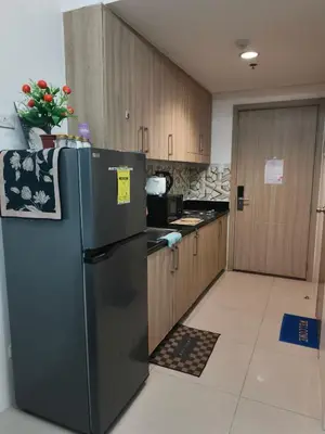 a kitchen with a black refrigerator and wooden cabinets at Shore Recidences Mall Of Asia Chullen in Manila