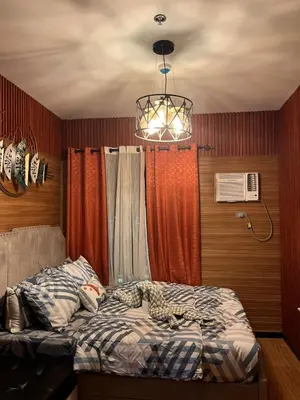 a bedroom with a bed and a chandelier at Modern 1BR Condo in Pasay With Balcony City View Free Swimming Pool Near NAIA Airport, PICC, CCP, MOA in Manila
